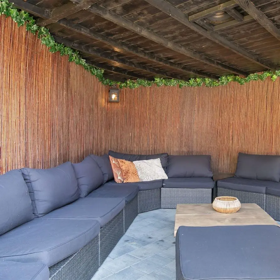 Loungeset met donkergrijze kussens op een overdekt terras op Bungalowpark Boerhaarsveld