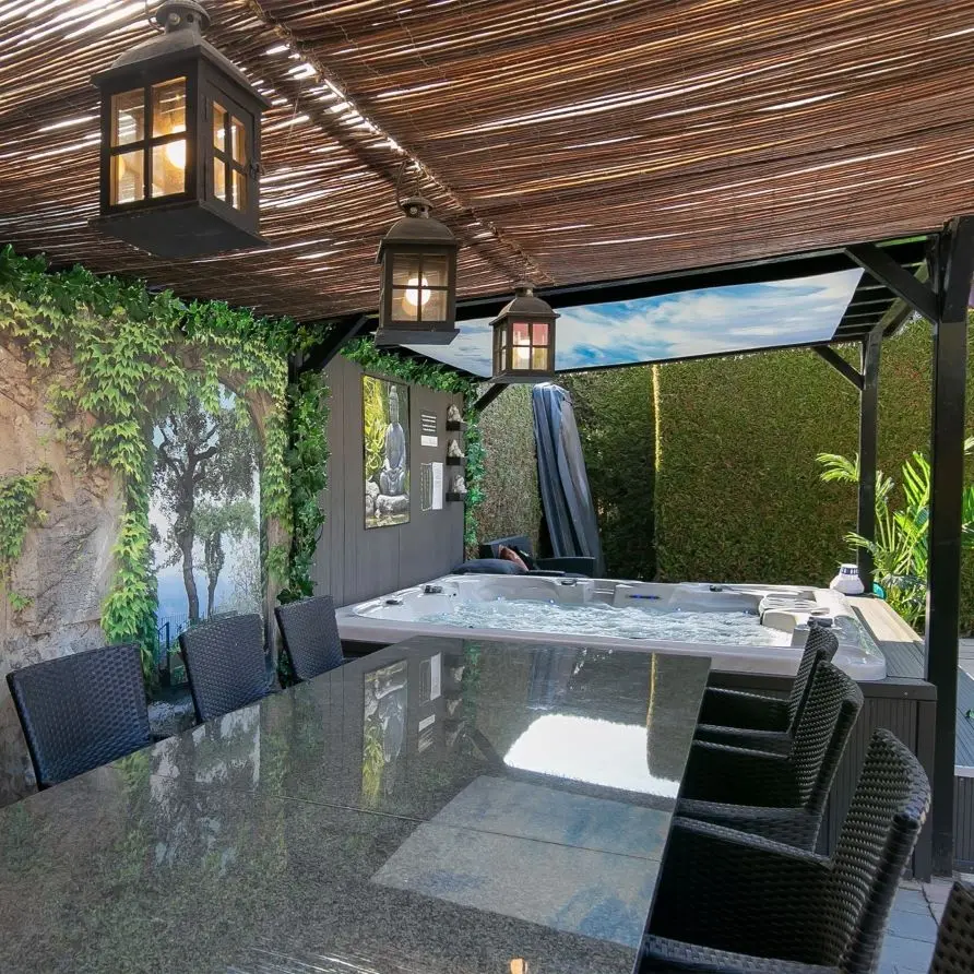 Eettafel met stoelen en een jacuzzi op een terras op Bungalowpark Boerhaarsveld